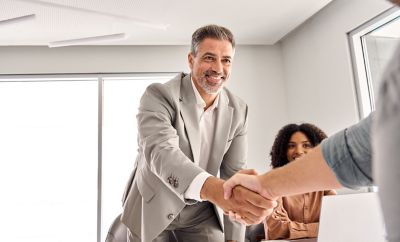 Two people shaking hands and one observing, Cloud Advisory Services | DXC Technology